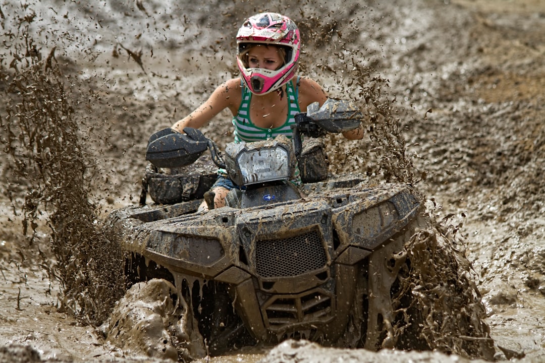 An ATV rider in a full-face helmet churning through mud, the gear the Mississippi UTV helmet law requires only for riders under sixteen.